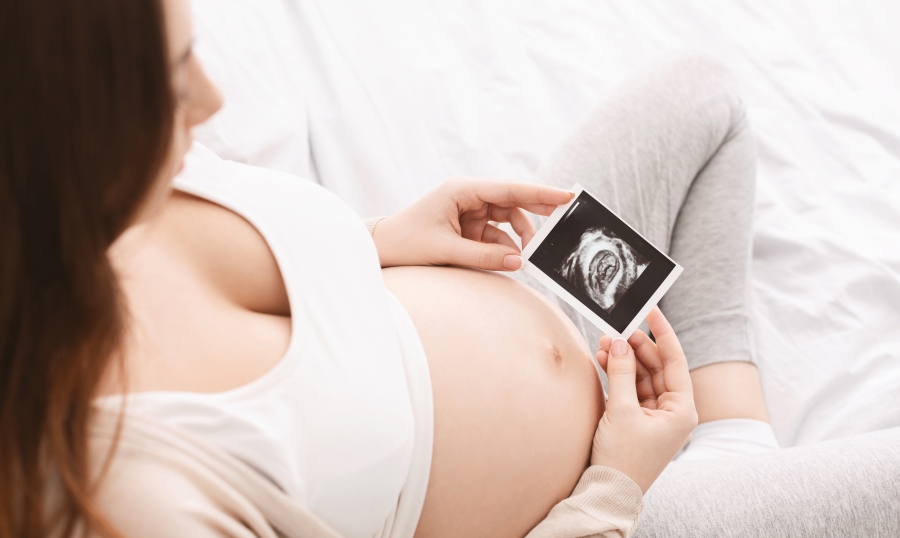 A surrogate mother smiles as she looks down at a sonogram