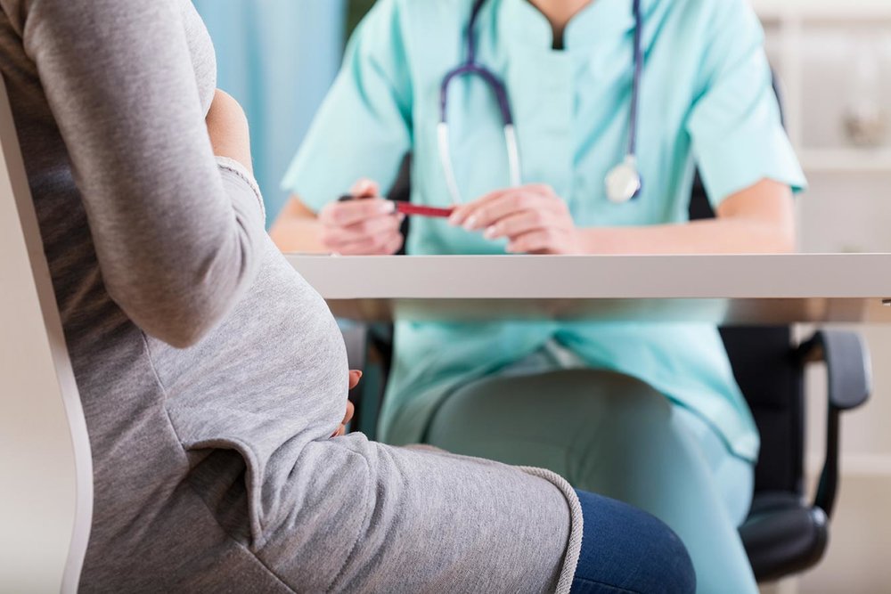 A pregnant surrogate mother meets with her physician.