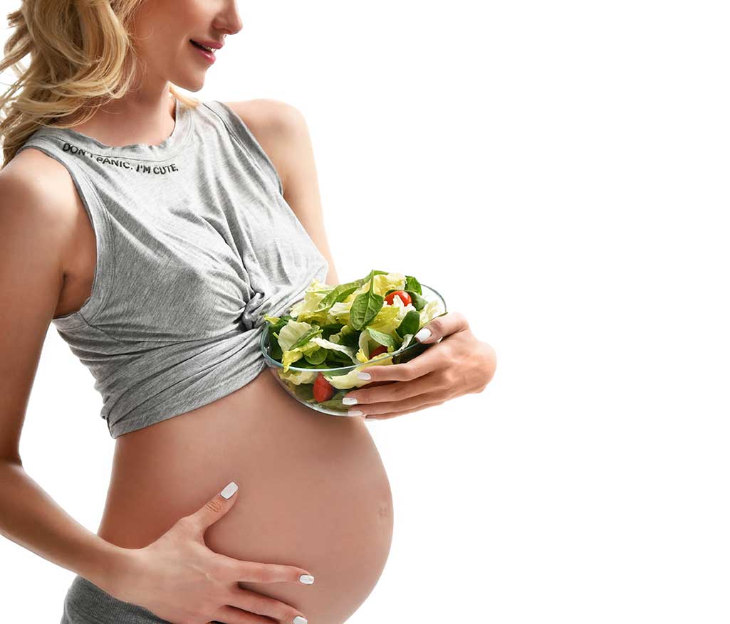 pregnant woman holding a salad