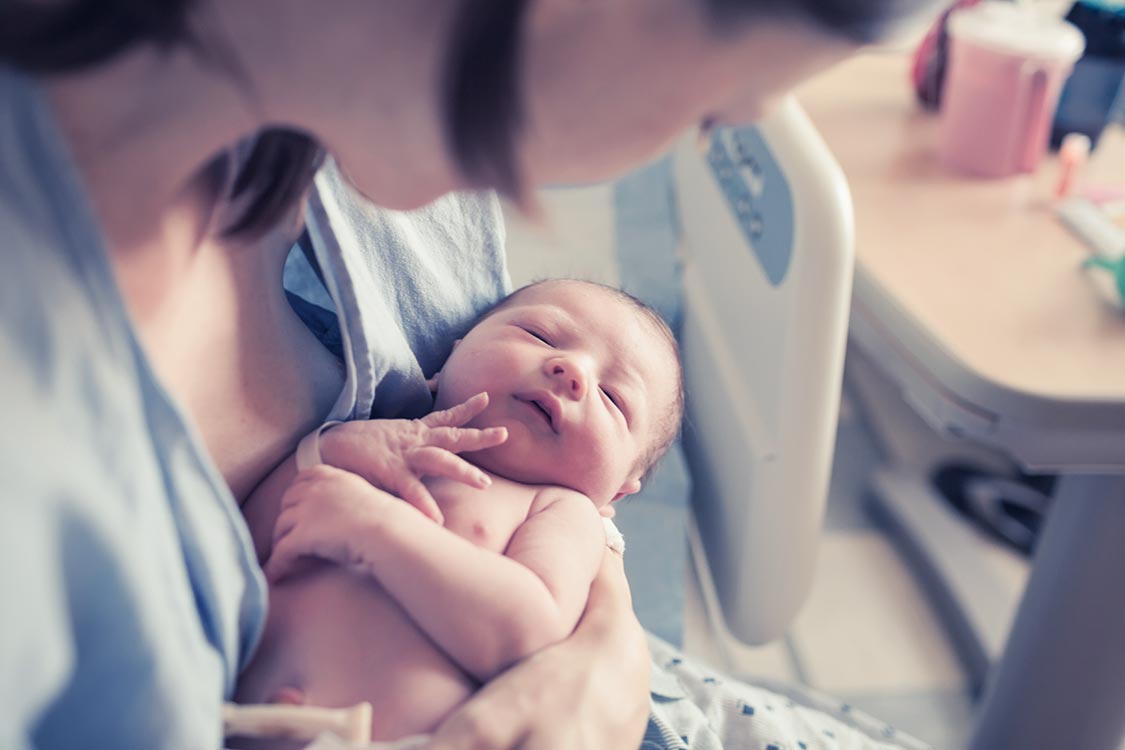 surrogate mother holding baby in the hospital after delivery